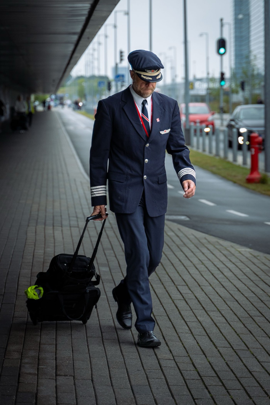A uniformed airline captain walking to the terminal with a flight bag.