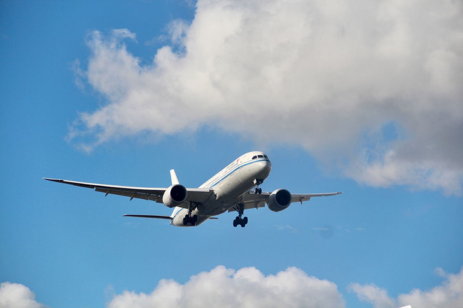 A commercial airliner climbing into a bright blue sky.